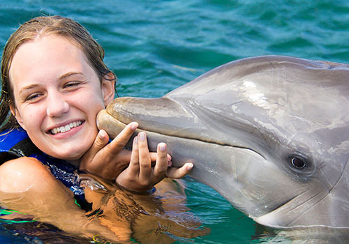 women being kissed by a dolphin at the dolphin experience Punta Cana